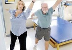 Physical Therapist and patient stretching their arms and legs.