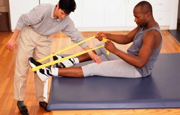 Man using a band to stretch ankle.