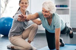 Physical therapist assisting patient on a balance and core exercise.