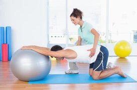 Patient is using medicine ball to stretch back.