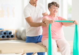 Physical Therapist assisting patient with her band exercise.