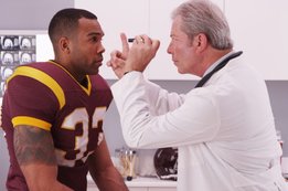 Provider examining football players eyes.